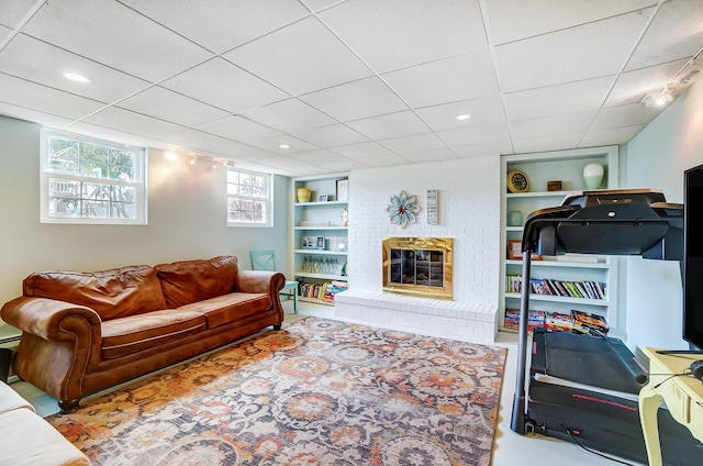 living room featuring a paneled ceiling, a fireplace, and built in shelves