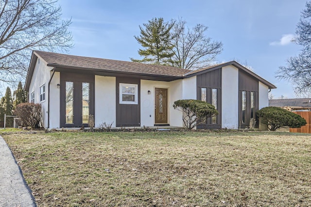 view of front facade featuring roof with shingles, a front yard, and fence