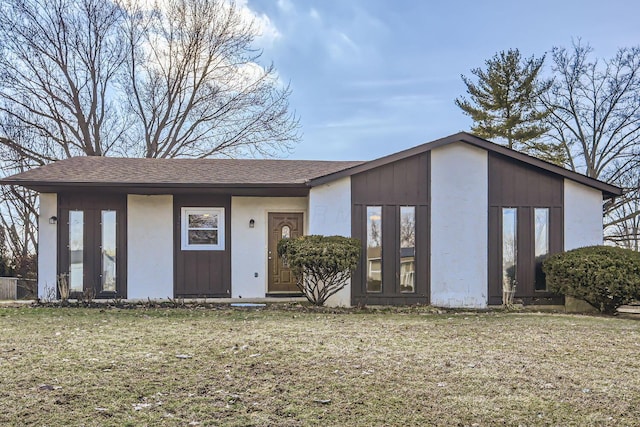 view of front facade with roof with shingles and a front lawn