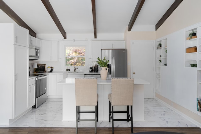 kitchen featuring a kitchen island, sink, a breakfast bar area, white cabinets, and stainless steel appliances