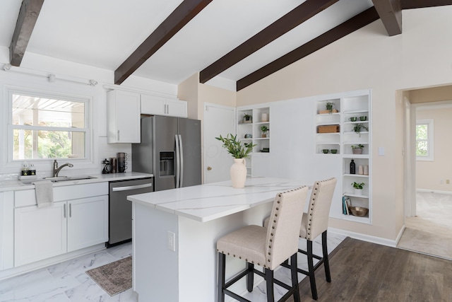 kitchen with sink, stainless steel appliances, a center island, light stone countertops, and white cabinets