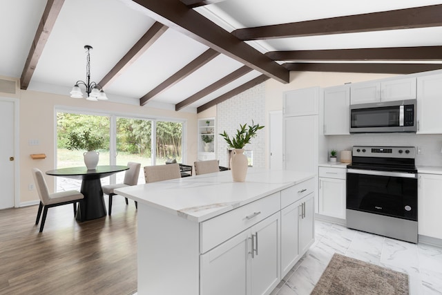 kitchen with white cabinetry, decorative light fixtures, a center island, appliances with stainless steel finishes, and light stone countertops