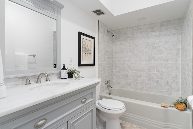 full bathroom featuring vanity, tiled shower / bath, and toilet