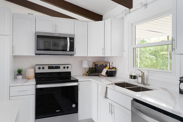 kitchen with stainless steel appliances, beam ceiling, sink, and white cabinets