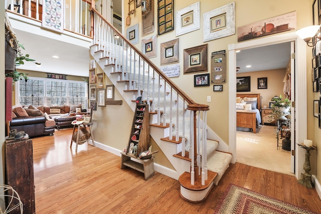 stairway with a towering ceiling and hardwood / wood-style floors