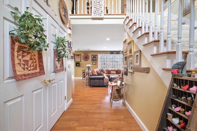 foyer entrance featuring a towering ceiling and light hardwood / wood-style flooring