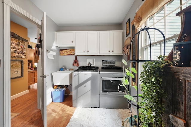 washroom with cabinets, sink, washer and clothes dryer, and light hardwood / wood-style flooring