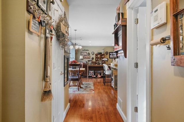 hall featuring hardwood / wood-style floors and a notable chandelier