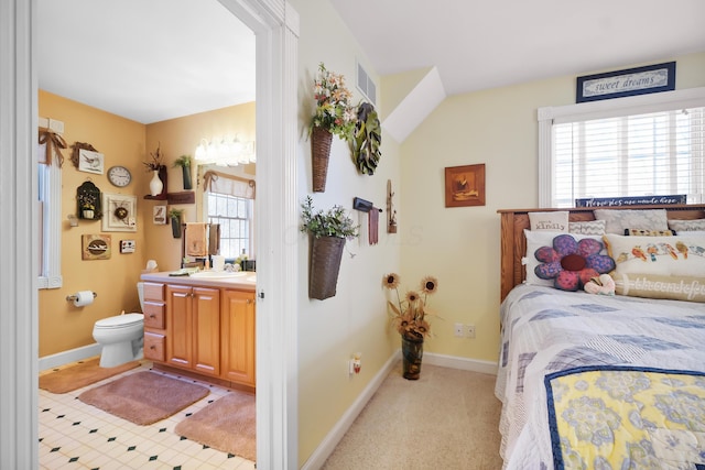 carpeted bedroom with ensuite bathroom and sink