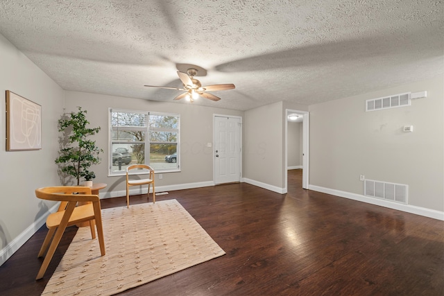 sitting room with dark wood-type flooring, a textured ceiling, and ceiling fan