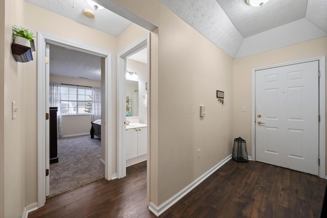 foyer entrance featuring baseboards, lofted ceiling, a textured ceiling, and dark wood finished floors