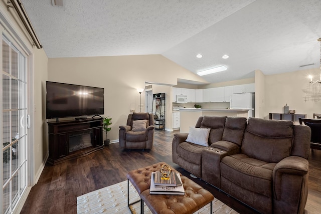 living area with lofted ceiling, a textured ceiling, a glass covered fireplace, dark wood-style floors, and baseboards