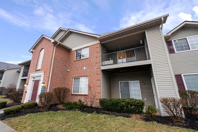 exterior space with a front lawn, brick siding, and a balcony