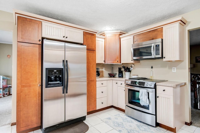 kitchen featuring stainless steel appliances, light tile patterned floors, and a textured ceiling