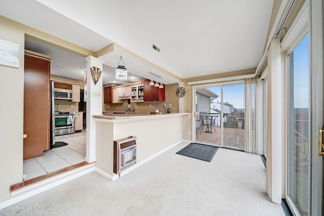 kitchen with stainless steel appliances, light carpet, heating unit, and kitchen peninsula