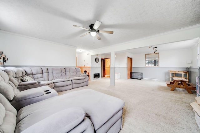 living room with a textured ceiling, baseboard heating, ornamental molding, carpet floors, and ceiling fan