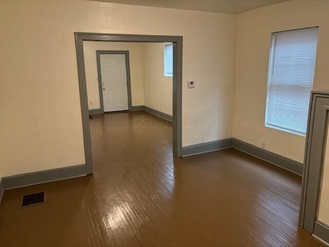 spare room with baseboards, visible vents, and dark wood finished floors