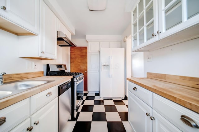 kitchen featuring appliances with stainless steel finishes, wood counters, white cabinetry, sink, and exhaust hood