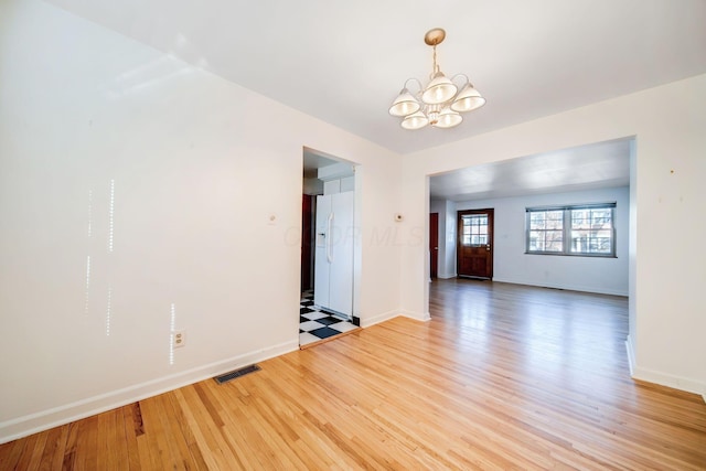 spare room with light wood-type flooring and a chandelier