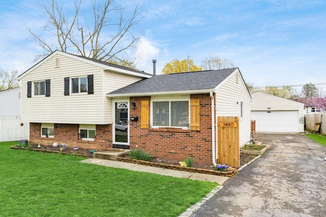 tri-level home featuring a detached garage, an outbuilding, a front yard, fence, and brick siding