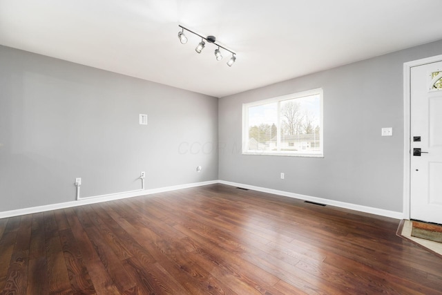 interior space with track lighting, dark wood finished floors, visible vents, and baseboards
