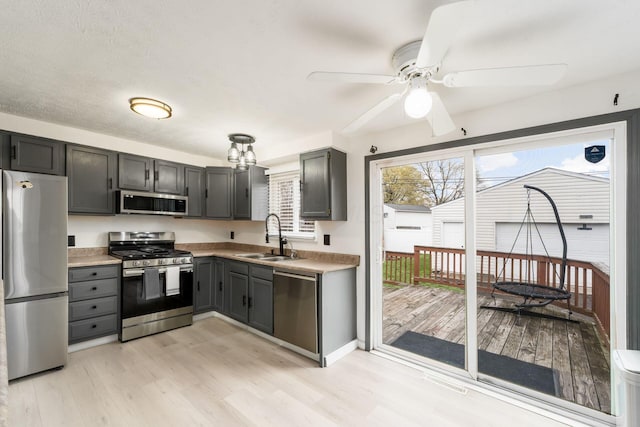 kitchen featuring a sink, stainless steel appliances, a ceiling fan, light wood-style flooring, and light countertops