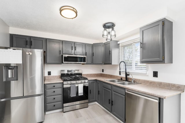 kitchen with stainless steel appliances, light countertops, gray cabinets, and a sink