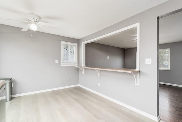 unfurnished room featuring baseboards, light wood-type flooring, and ceiling fan