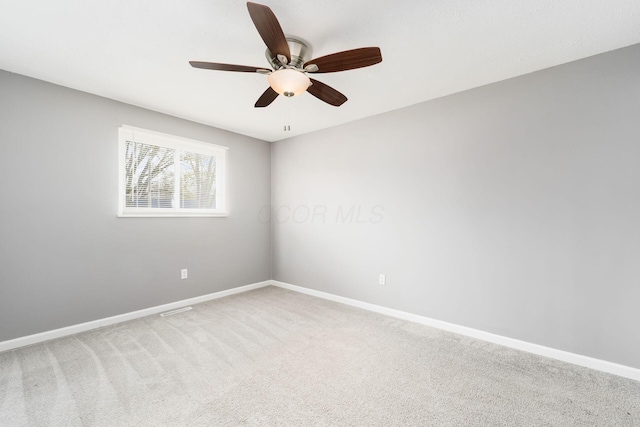 carpeted spare room featuring ceiling fan, visible vents, and baseboards