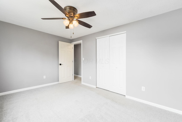 unfurnished bedroom featuring light colored carpet, ceiling fan, a closet, and baseboards