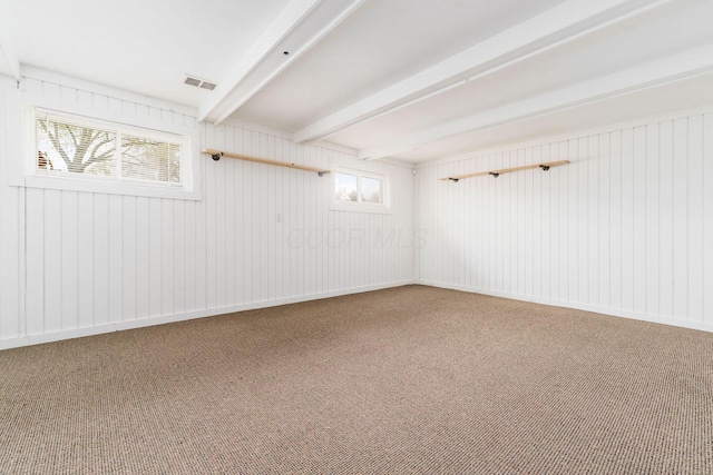 carpeted empty room with visible vents and beamed ceiling