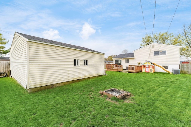 view of yard featuring a deck, fence, and central AC unit