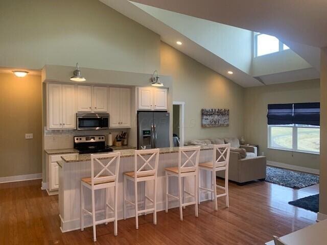 kitchen featuring white cabinets, a kitchen bar, stainless steel appliances, and open floor plan