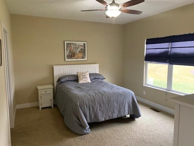 bedroom featuring light carpet, ceiling fan, visible vents, and baseboards