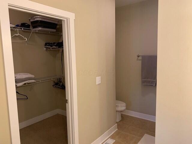 bathroom featuring toilet, visible vents, baseboards, and a walk in closet