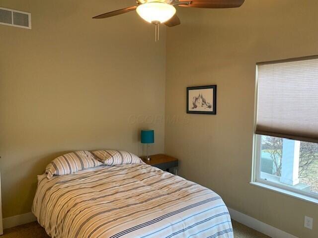 carpeted bedroom with a ceiling fan, visible vents, and baseboards