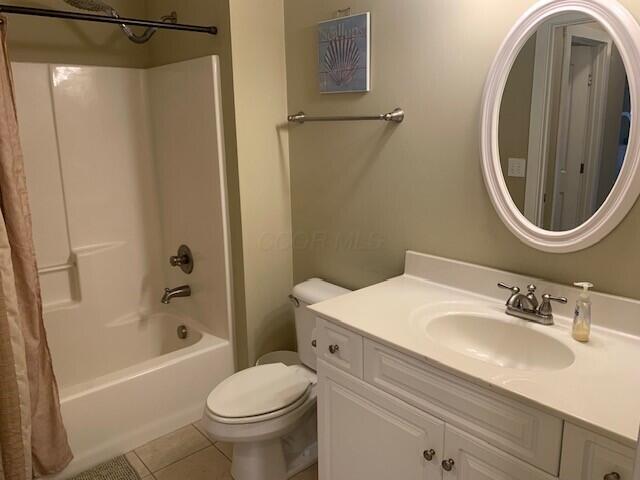 bathroom featuring shower / bath combo with shower curtain, vanity, toilet, and tile patterned floors