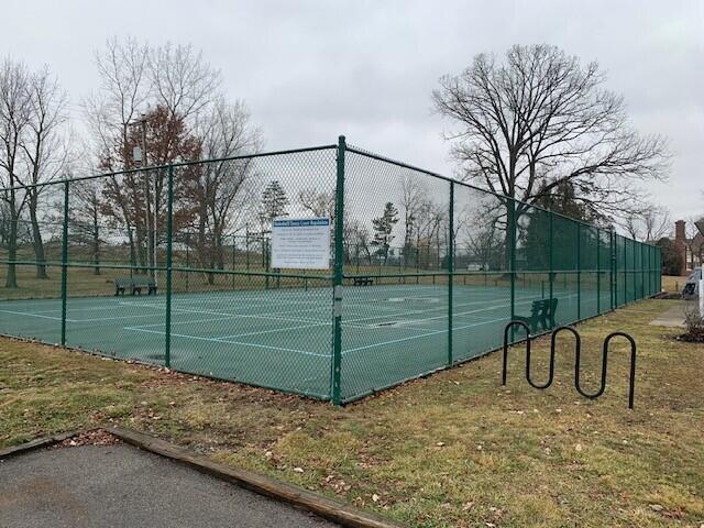 view of sport court featuring fence and a lawn