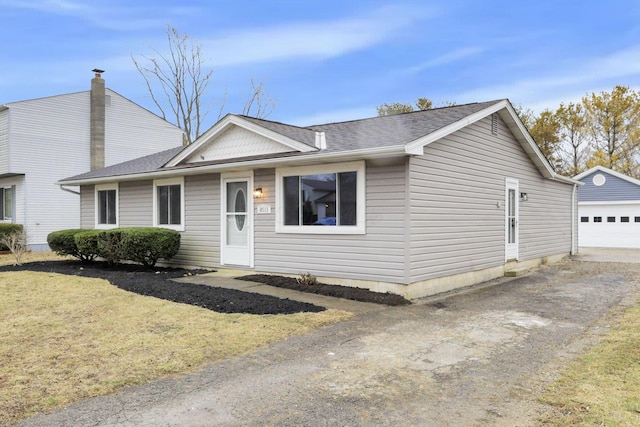 view of front of home featuring a garage, an outdoor structure, and a front lawn