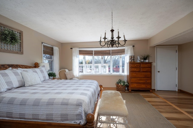 bedroom featuring a notable chandelier, wood-type flooring, and a textured ceiling