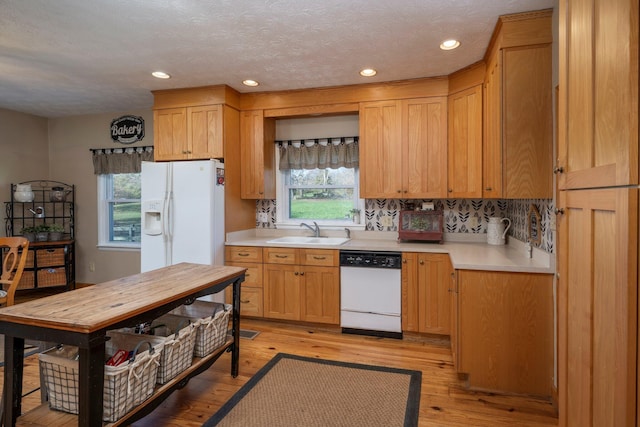 kitchen with sink, white appliances, backsplash, a textured ceiling, and light wood-type flooring