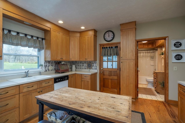 kitchen with wood counters, sink, light hardwood / wood-style flooring, dishwasher, and decorative backsplash