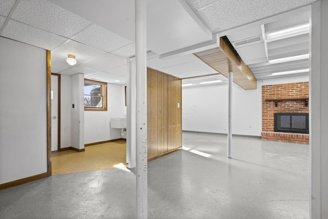 basement featuring a paneled ceiling and a fireplace