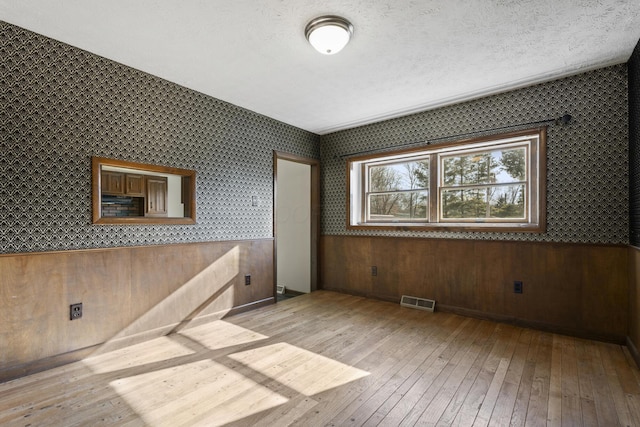 empty room with light hardwood / wood-style floors and a textured ceiling