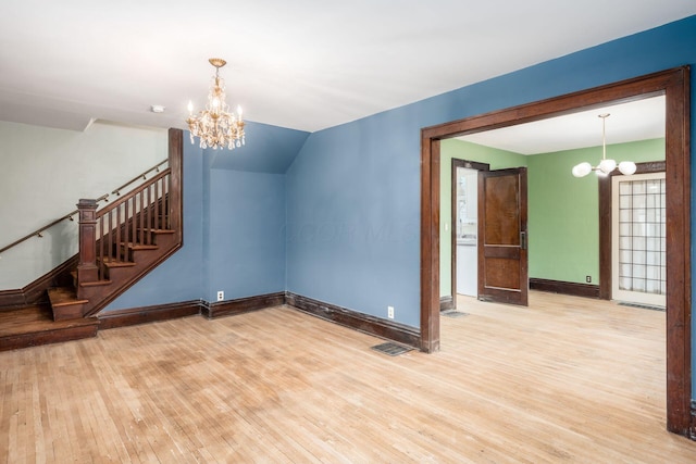 unfurnished living room with lofted ceiling, a chandelier, and light hardwood / wood-style flooring