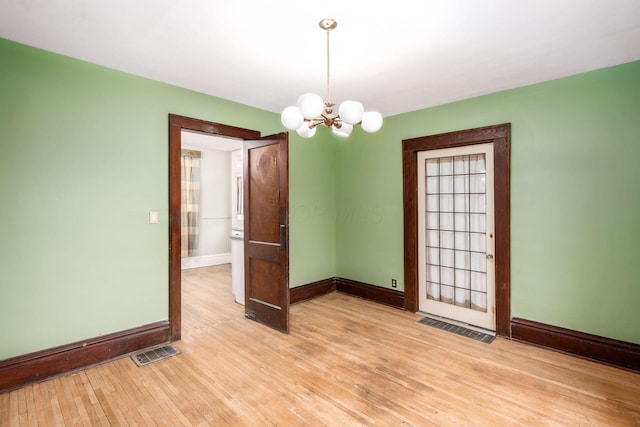 spare room featuring an inviting chandelier and light hardwood / wood-style flooring