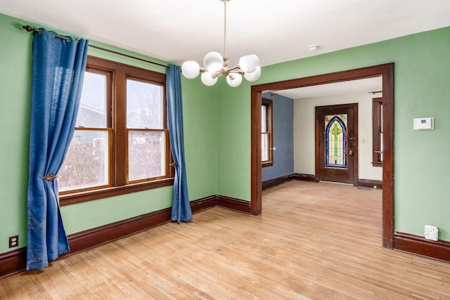 spare room with an inviting chandelier and light wood-type flooring