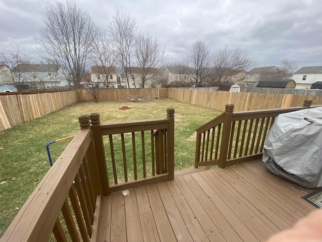 wooden deck with a grill, a lawn, and an outdoor fire pit