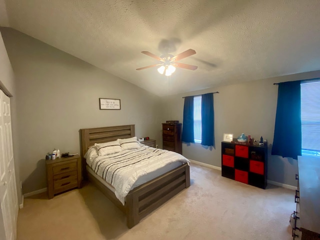 bedroom with vaulted ceiling, light colored carpet, ceiling fan, and a textured ceiling