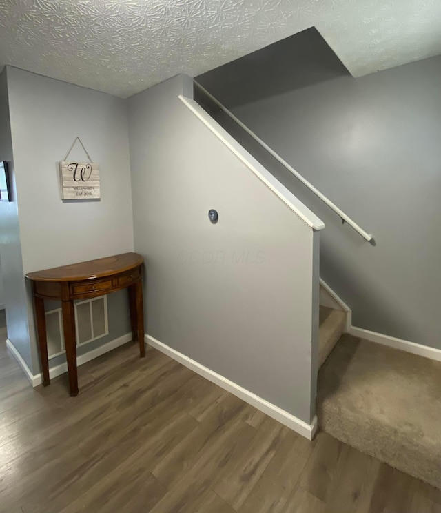 stairway featuring wood-type flooring and a textured ceiling